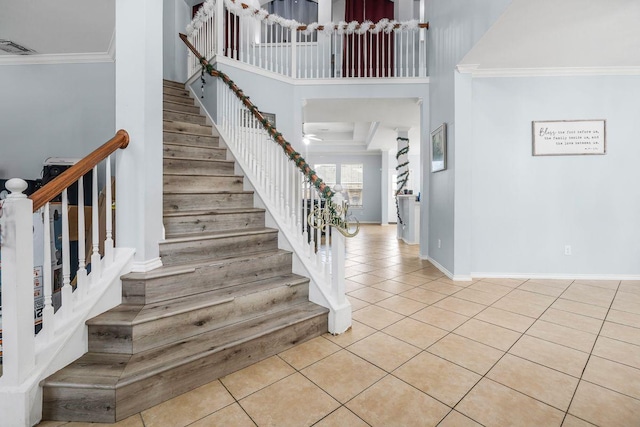 tiled foyer with crown molding and a high ceiling