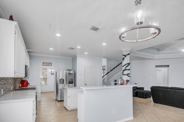 kitchen featuring white cabinetry, a center island, ornamental molding, appliances with stainless steel finishes, and decorative backsplash