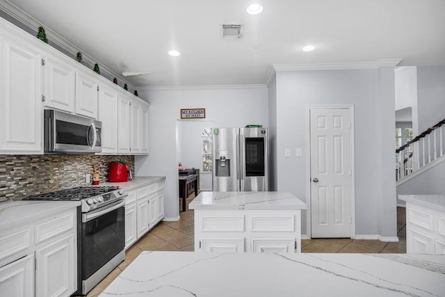 kitchen with tasteful backsplash, appliances with stainless steel finishes, light tile patterned floors, and white cabinets