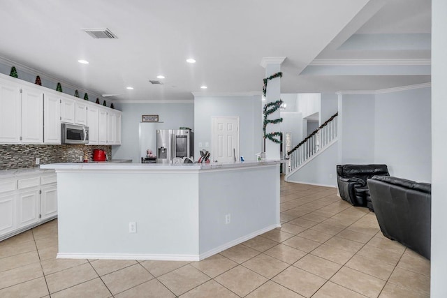 kitchen featuring stainless steel appliances, light tile patterned floors, a center island with sink, and white cabinets