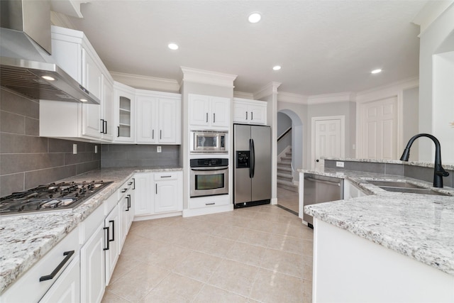 kitchen with white cabinets, wall chimney range hood, appliances with stainless steel finishes, and sink