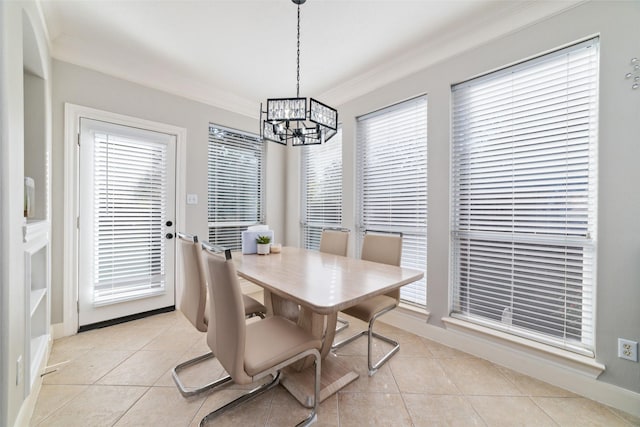 dining area with light tile patterned floors, ornamental molding, and a notable chandelier