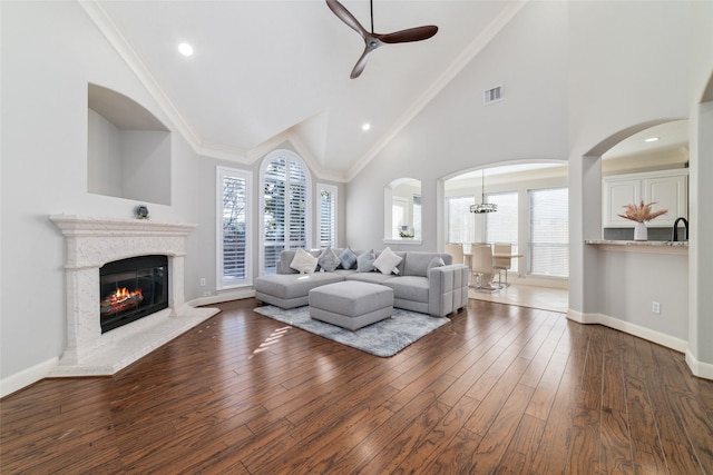 living room featuring ceiling fan, dark hardwood / wood-style floors, high vaulted ceiling, and crown molding