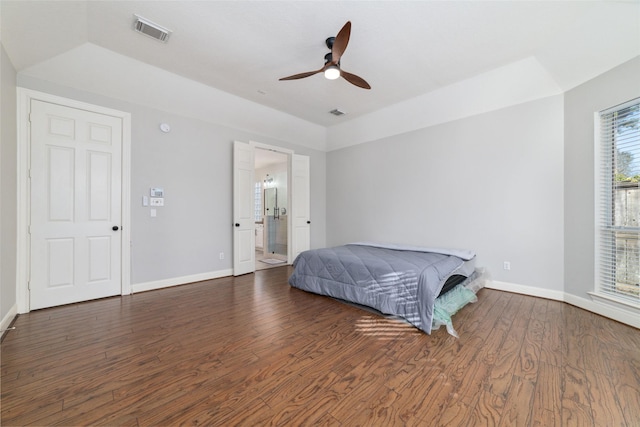 bedroom with ceiling fan, connected bathroom, a raised ceiling, and dark hardwood / wood-style flooring