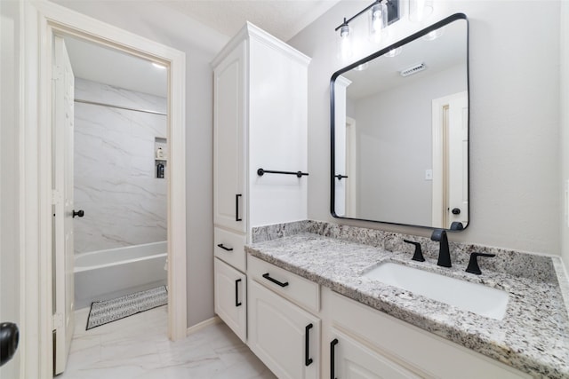 bathroom with tiled shower / bath combo and vanity