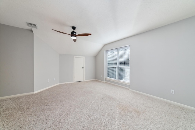 carpeted spare room with vaulted ceiling and ceiling fan