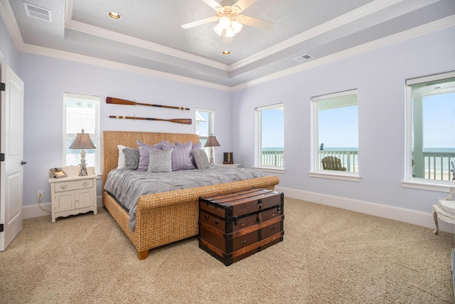 carpeted bedroom featuring crown molding, a tray ceiling, ceiling fan, and a water view