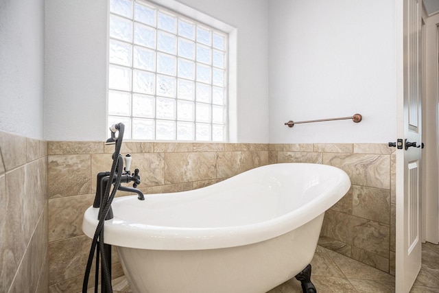 full bathroom with tile walls, a freestanding tub, and wainscoting