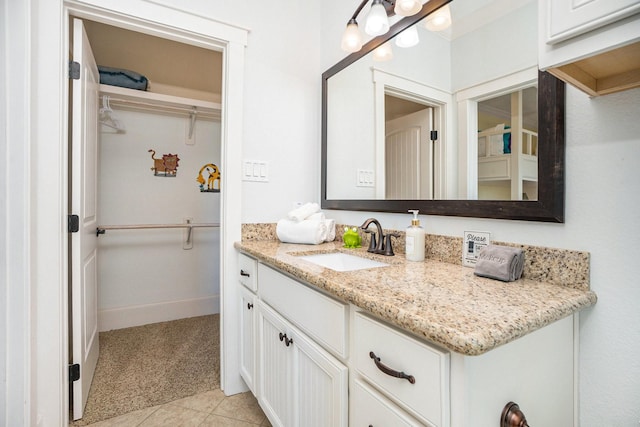 bathroom with tile patterned floors, vanity, a spacious closet, and baseboards