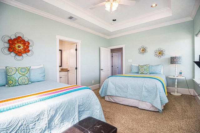 bedroom with crown molding, connected bathroom, a tray ceiling, and carpet floors