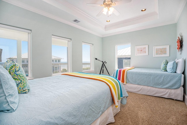 carpeted bedroom with ceiling fan, ornamental molding, and a tray ceiling