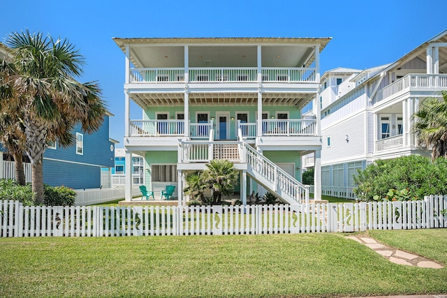 raised beach house with a front lawn, a fenced front yard, and stairway