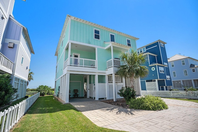 view of front of home with a balcony, a carport, and a front lawn