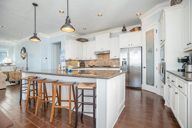 kitchen with white cabinetry, stainless steel appliances, a kitchen bar, and a center island with sink