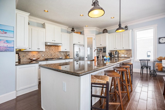 kitchen with crown molding, appliances with stainless steel finishes, dark hardwood / wood-style floors, an island with sink, and white cabinets