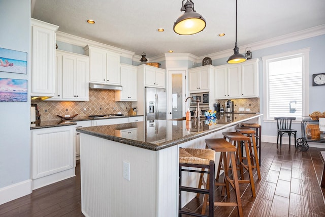 kitchen featuring a sink, under cabinet range hood, stainless steel appliances, ornamental molding, and dark wood-style flooring