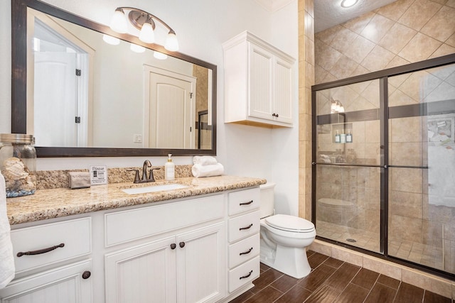 full bathroom with toilet, vanity, a stall shower, and wood tiled floor