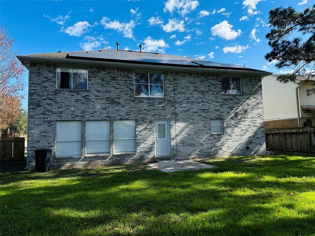 back of property featuring a lawn and solar panels