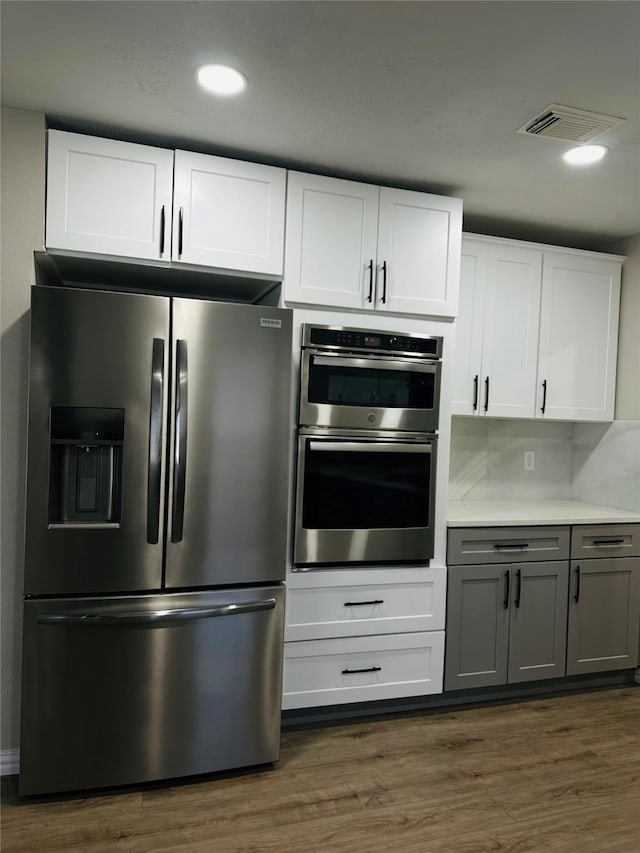 kitchen featuring white cabinets, stainless steel appliances, dark hardwood / wood-style flooring, and gray cabinets