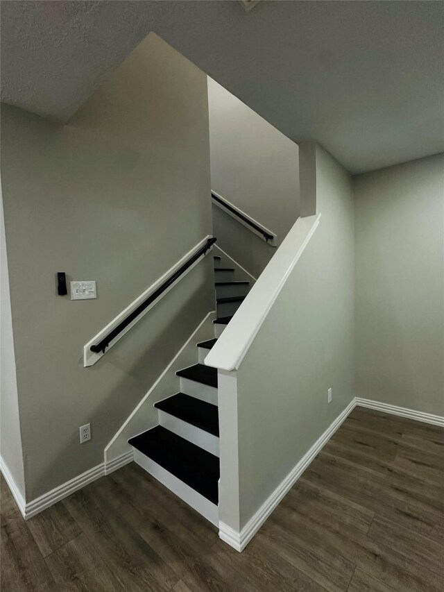 stairs featuring hardwood / wood-style flooring and a textured ceiling