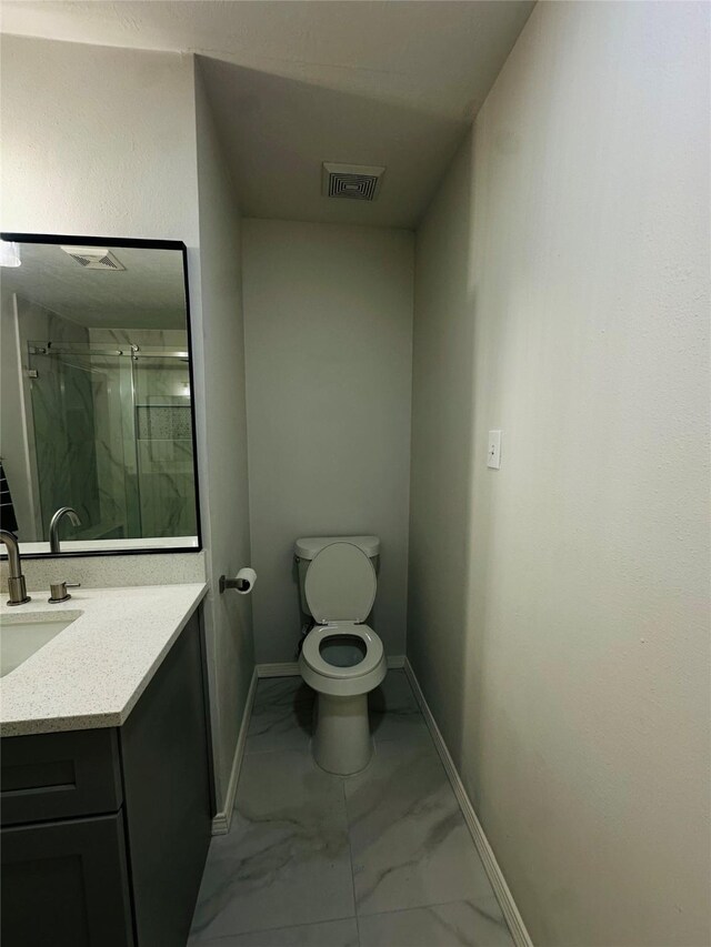 bathroom featuring toilet, a shower with shower door, and vanity