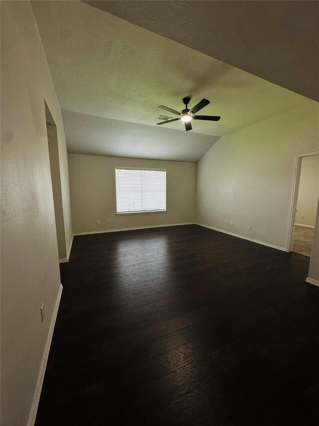 empty room with ceiling fan, dark hardwood / wood-style floors, and lofted ceiling