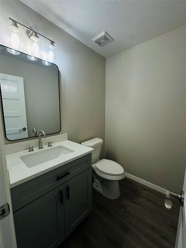 bathroom featuring vanity, toilet, hardwood / wood-style floors, and a textured ceiling