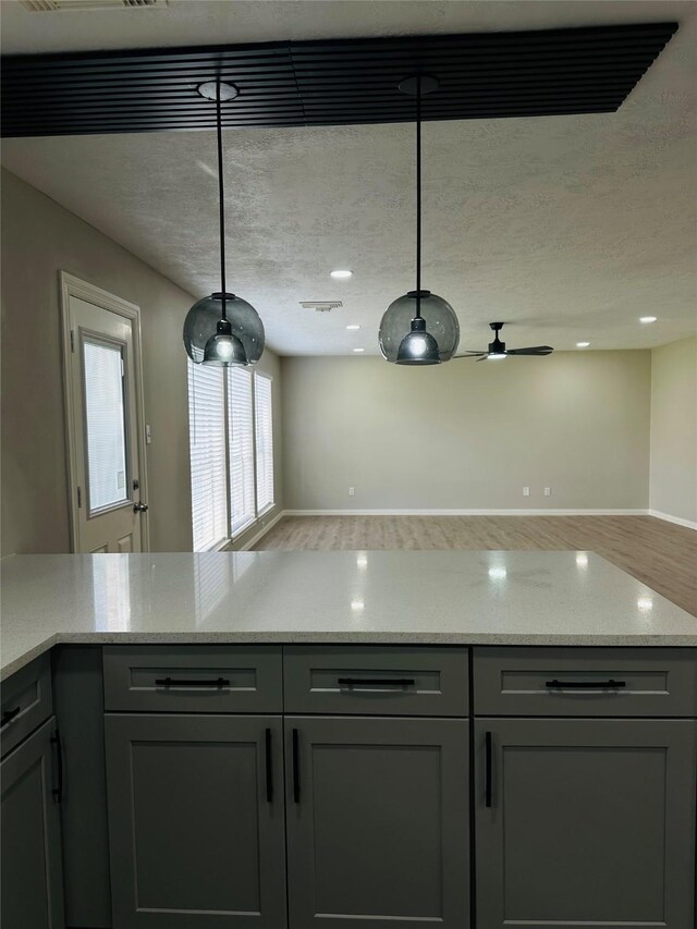 kitchen with decorative light fixtures, gray cabinets, and light stone counters