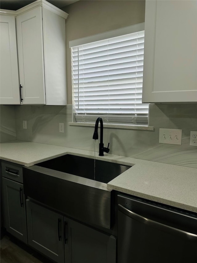 kitchen with dishwashing machine, sink, and white cabinetry