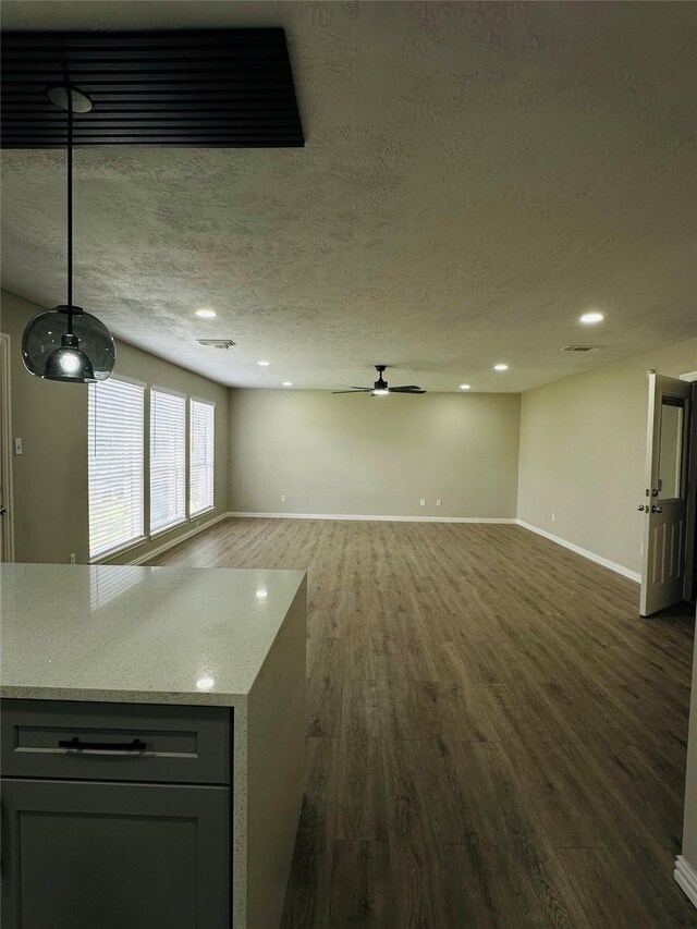 unfurnished living room with ceiling fan, dark hardwood / wood-style floors, and a textured ceiling