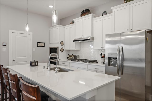 kitchen featuring a kitchen breakfast bar, appliances with stainless steel finishes, sink, decorative light fixtures, and a kitchen island with sink