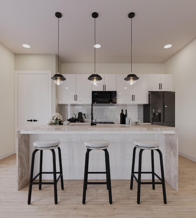 kitchen with black appliances, a kitchen bar, decorative backsplash, and white cabinets