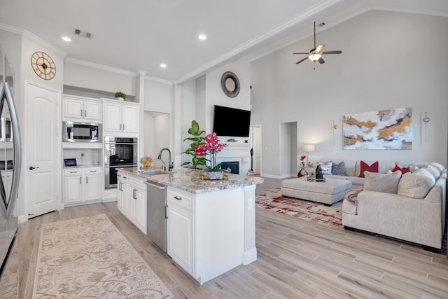 kitchen with sink, stainless steel appliances, an island with sink, and white cabinets