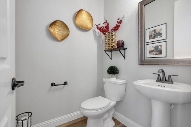 bathroom with wood-type flooring, toilet, and sink