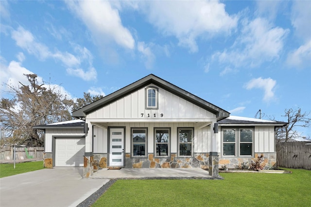 view of front facade featuring covered porch, a front yard, and a garage