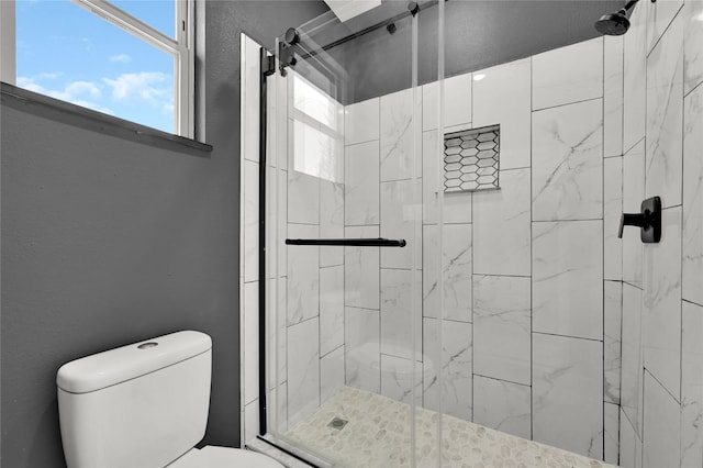 bathroom featuring a shower with shower door and toilet