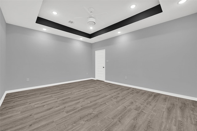 spare room featuring ceiling fan, light hardwood / wood-style flooring, and a tray ceiling