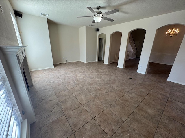 unfurnished living room with ceiling fan with notable chandelier, a textured ceiling, and tile patterned floors