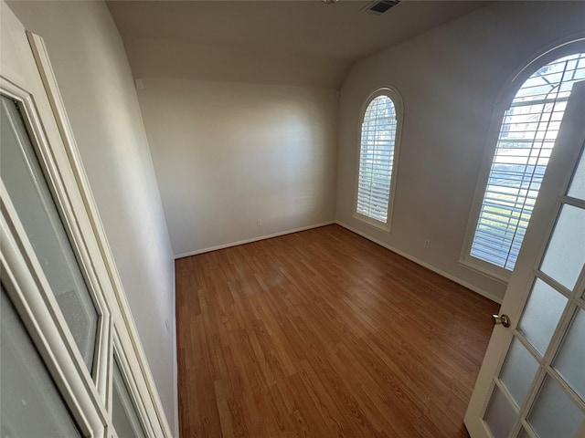 empty room with hardwood / wood-style flooring and vaulted ceiling