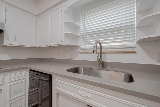 kitchen featuring white cabinetry, black dishwasher, and sink