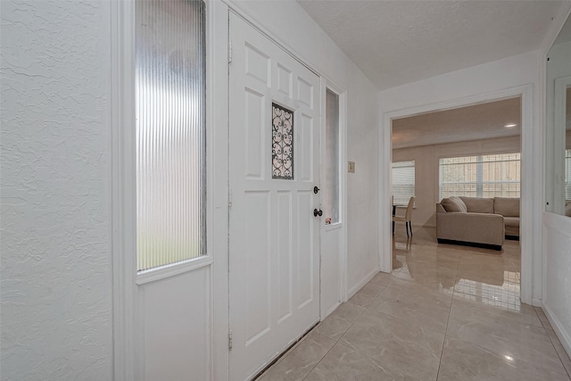 hall with a textured ceiling and light tile patterned floors