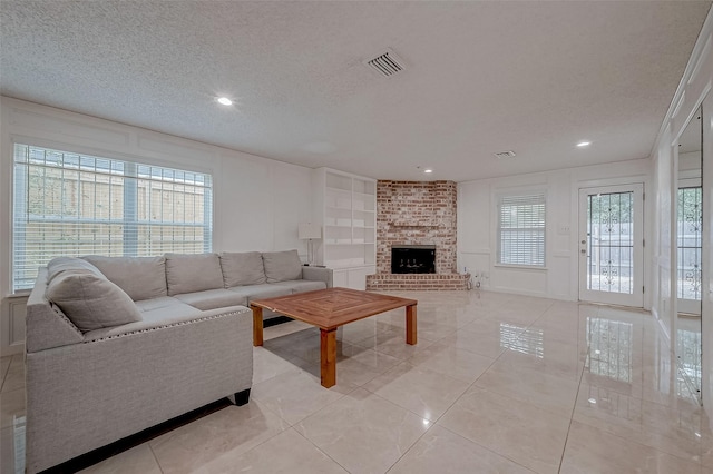 living room with a fireplace, a textured ceiling, and light tile patterned flooring