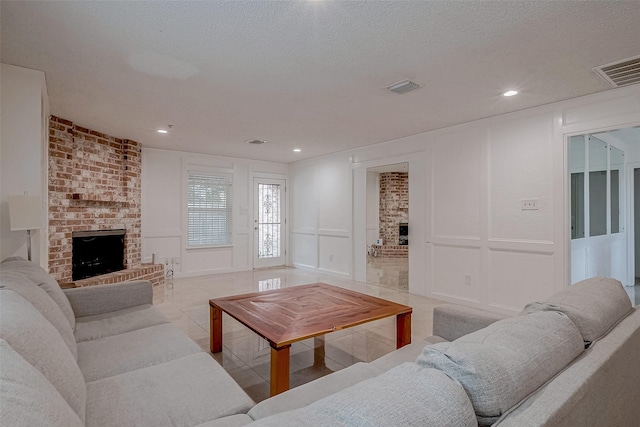 tiled living room featuring a fireplace and a textured ceiling