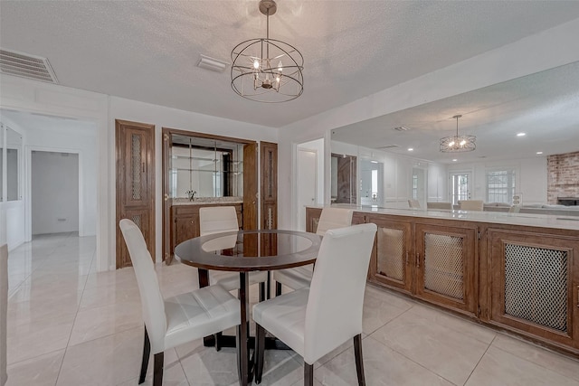 tiled dining room with a textured ceiling and a notable chandelier