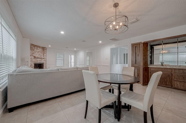 dining space featuring plenty of natural light, a fireplace, and a textured ceiling