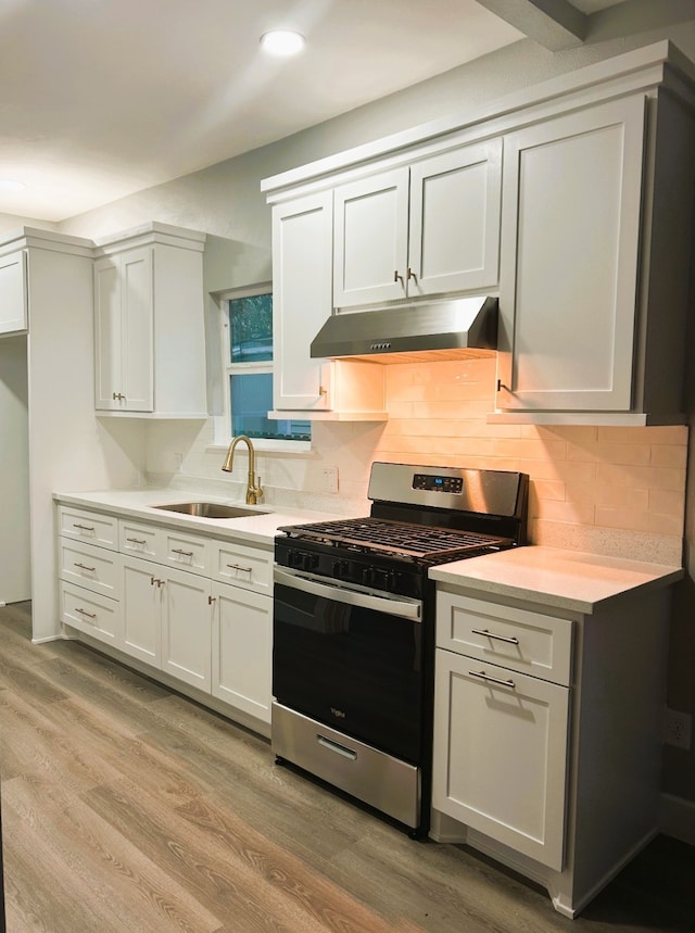 kitchen with backsplash, stainless steel gas range, sink, and light wood-type flooring