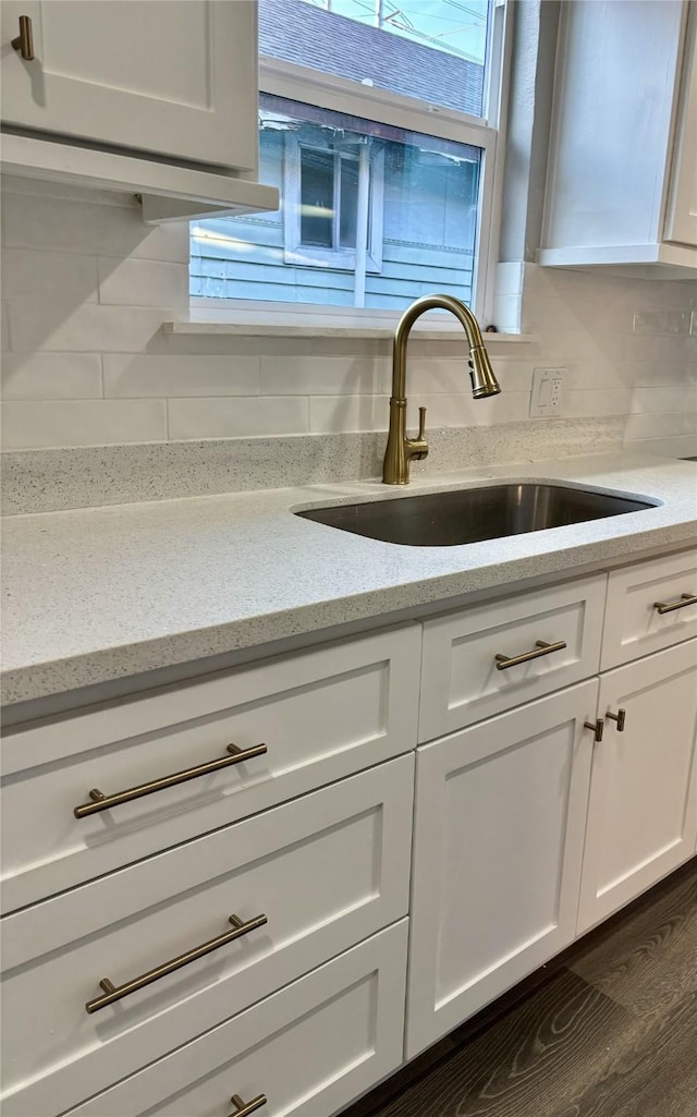 interior details with dark hardwood / wood-style floors, tasteful backsplash, sink, white cabinets, and light stone countertops