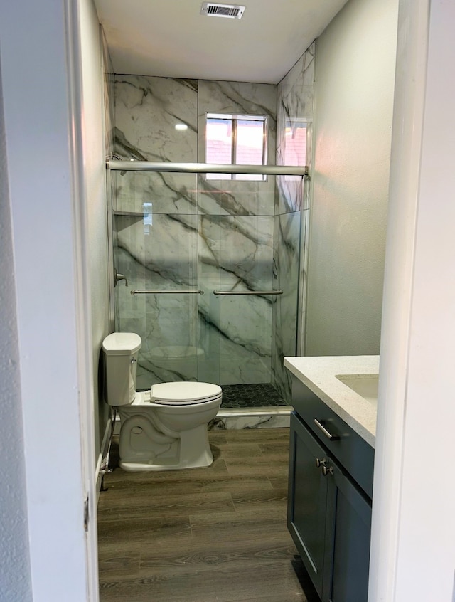 bathroom with wood-type flooring, toilet, a shower with door, and vanity