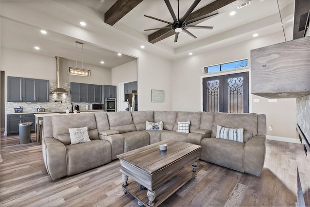 living room with wood-type flooring, beamed ceiling, a high ceiling, and french doors