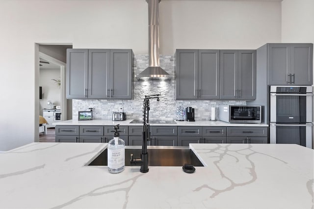 kitchen featuring appliances with stainless steel finishes, sink, tasteful backsplash, gray cabinetry, and light stone counters